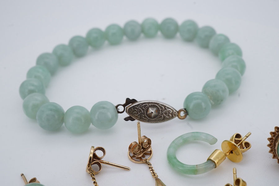 A collection of jadeite jewels, comprising: a bead bracelet with a silver clasp; together with three pairs of studs; one pair of hoop studs, one broken and restuck; and one pair of drop earrings, each set with jadeite, m
